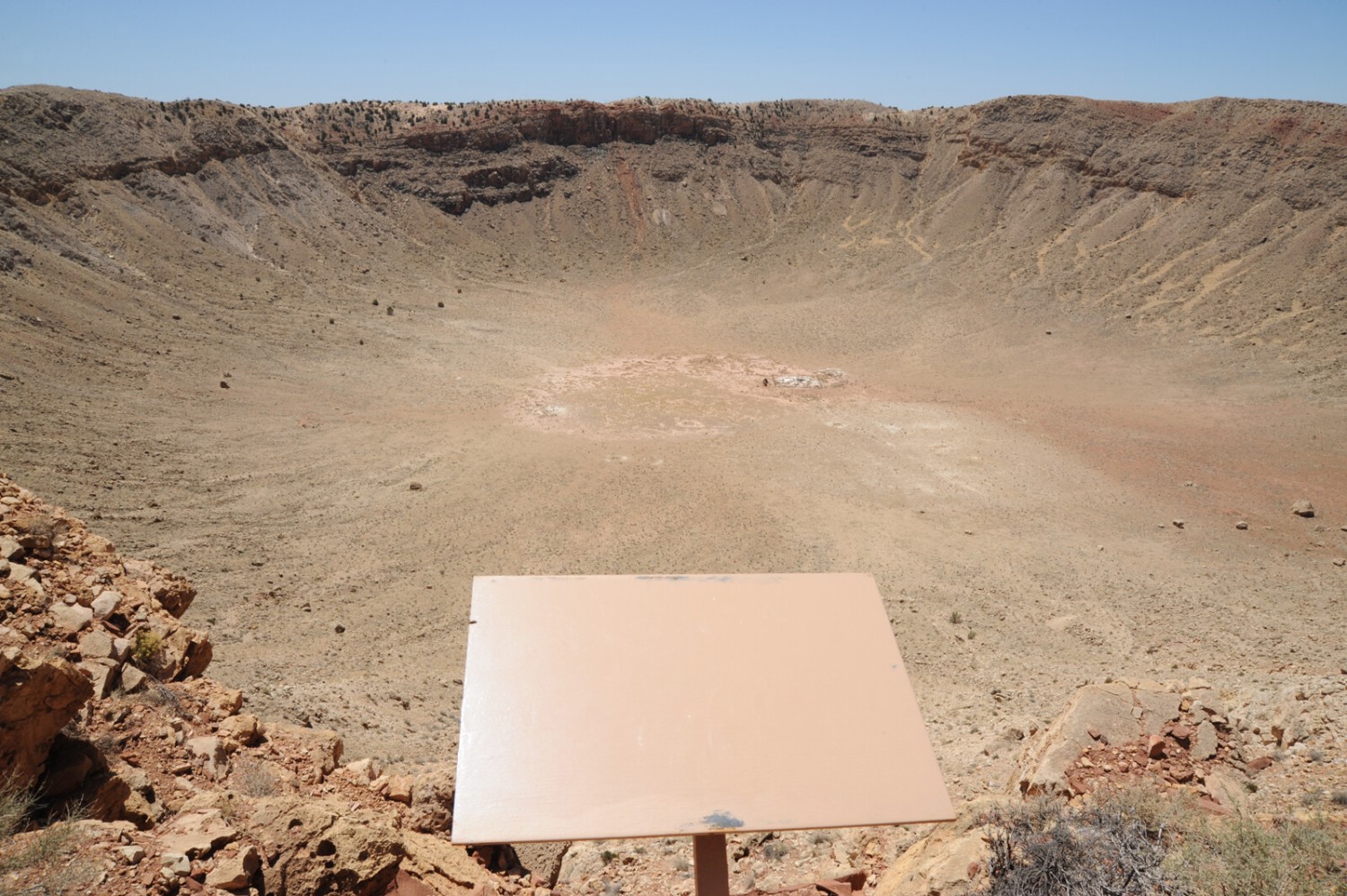 A blank sign in front of a crater.